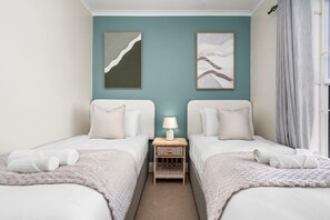 A twin room with two beds, a nightstand with a lamp, and artwork on the walls. - Sangrove Residence (Cape Town)