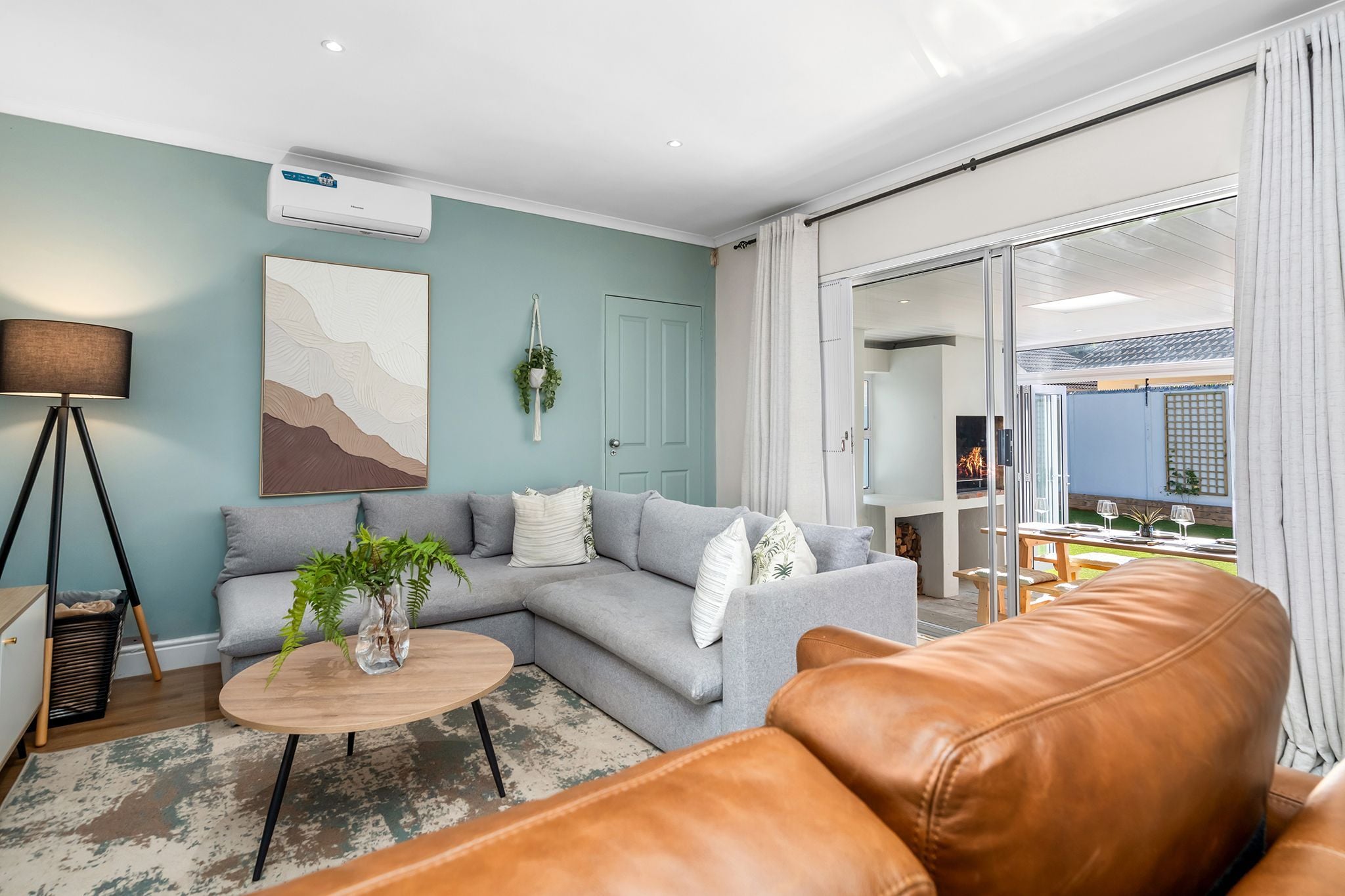 A living room with a sofa, a coffee table, a lamp, and a sliding glass door leading to an outdoor area.
