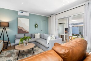 Una sala de estar con un sofá, una mesa de centro, una lámpara y un ventanal corredero que da a un espacio exterior.