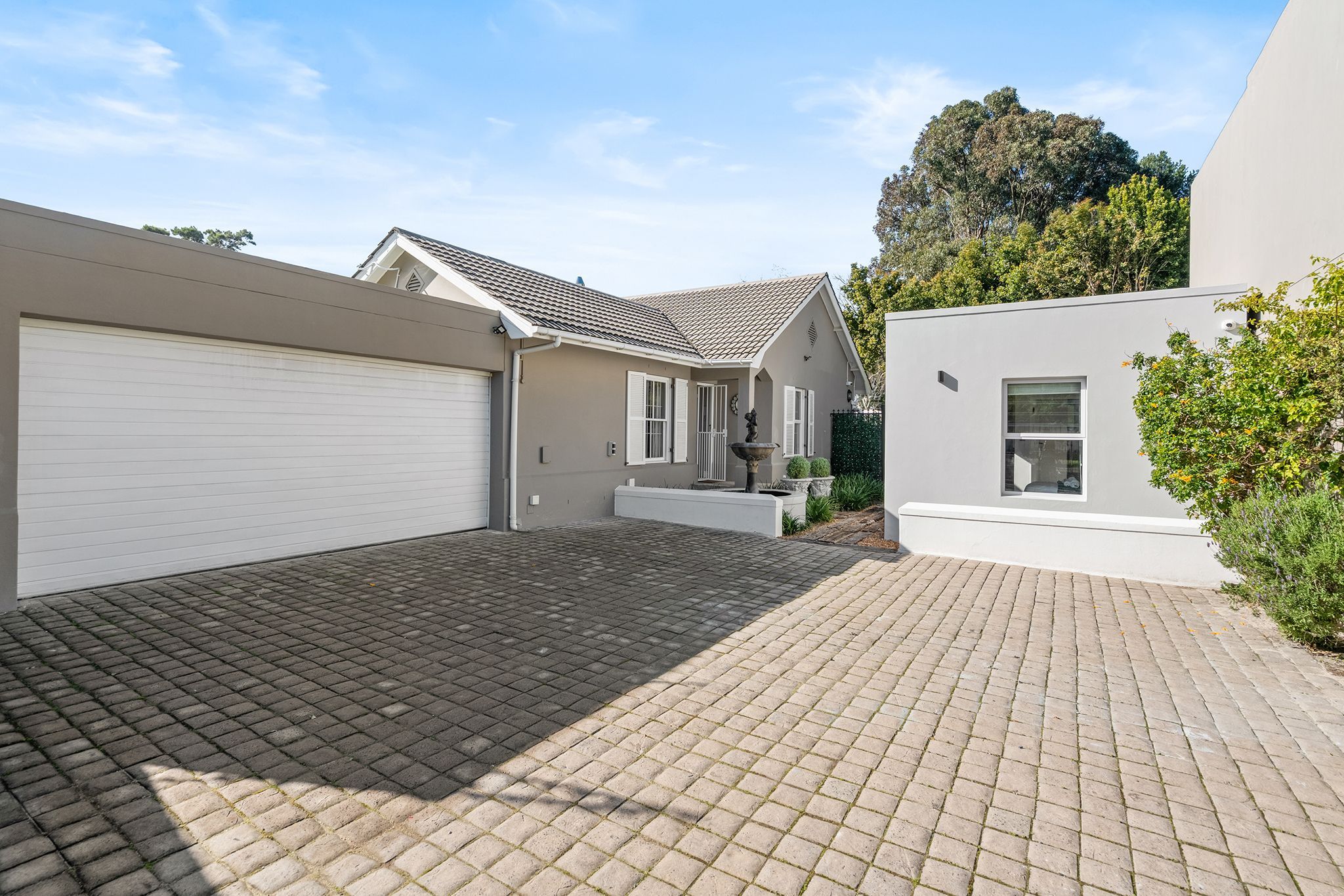 A residential property with a paved driveway, a garage, and a small garden area.