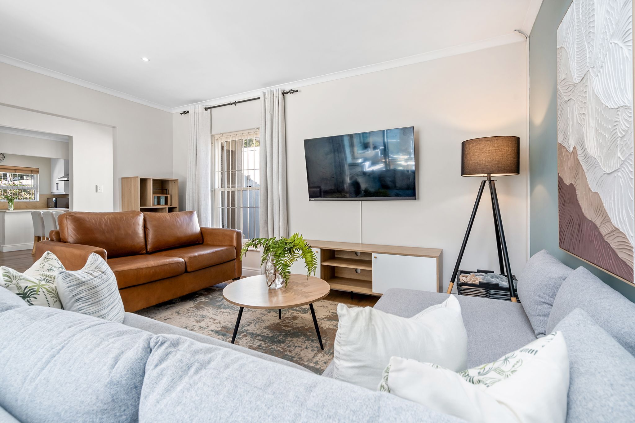 A modern living room with a leather sofa, a round coffee table, and a grey couch.