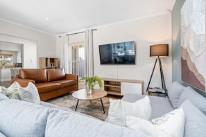 A modern living room with a leather sofa, a round coffee table, and a grey couch.