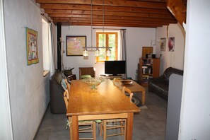 A dining area with a wooden table, chairs, a television, and a bookshelf. - La Bergerie – Private Pool (Cadrieu)