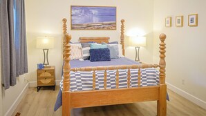 Ein Bett mit Baldachin, ein Kopfteil, zwei Nachttische, eine Wandleuchte, ein Gemälde und ein Fenster mit Vorhängen.