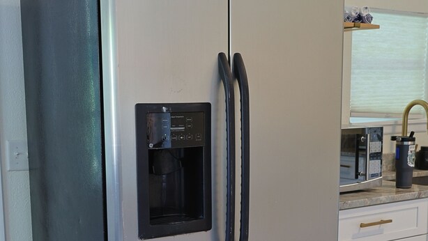 Ein Edelstahl-Kühlschrank mit integriertem Wasserspender, einer Mikrowelle und einem Spülbecken.