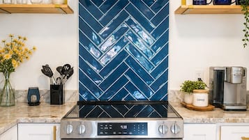 A kitchen with a stainless steel range hood, a digital clock, and a GE oven.