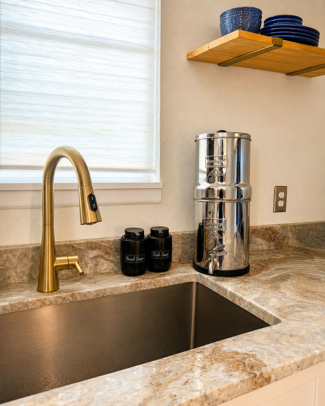 A kitchen with a gold faucet, a coffee maker, and two containers labeled 'Hand Soap' and 'Dish Soap' on the counter.
