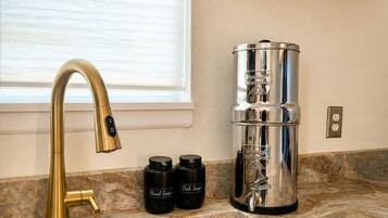 A kitchen with a gold faucet, a coffee maker, and two containers labeled 'Hand Soap' and 'Dish Soap' on the counter.