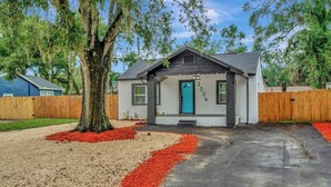 A single-story house with a blue door, surrounded by a wooden fence, and a driveway leading to the entrance. - 2 Bed Oasis 10 Minutes to Downtown (tampa)