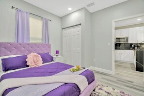 A bedroom with a large bed, a nightstand, a dresser, and a door leading to a kitchen. - 2 Bed Oasis 10 Minutes to Downtown (tampa)
