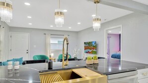 Una cocina moderna con una isla central, iluminación colgante y vistas a un patio trasero.