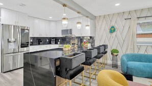 Una cocina moderna con una isla central, electrodomésticos de acero inoxidable y una zona de bar con taburetes.
