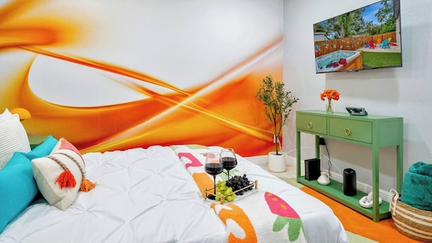 Un dormitorio con una cama, una mesita de noche verde, un cuadro y vistas al exterior.