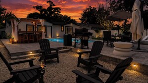 Un espace extérieur aménagé avec une terrasse, une piscine, des sièges et un barbecue.