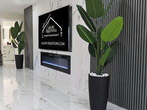 A modern lobby with a black signboard, a fireplace, and potted plants. - Lux 4 Bedroom Bayfront Retreat with Hot Tub & Dock (tampa)