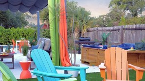 A backyard with outdoor furniture, including two chairs and a table, surrounded by greenery and a wooden fence. - Stay & Play Downtown Tampa Sleeps 10- HotTub & Bar (tampa)