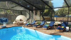 Una piscina con sillones de descanso y un aro de baloncesto.