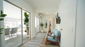 A modern interior with a sliding glass door leading to an outdoor area, a wooden floor, a striped rug, and a seating area with a sofa and chairs. - Tampa High Roller, Relax and Play (Tampa)