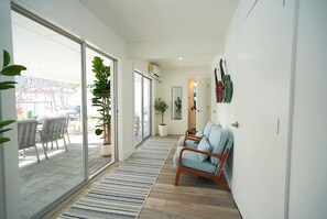 A modern interior with a sliding glass door leading to an outdoor area, a wooden floor, a striped rug, and a seating area with a sofa and chairs. - Tampa High Roller, Relax and Play (Tampa)