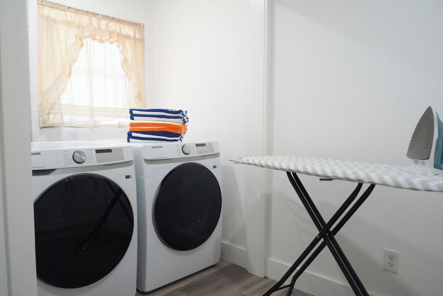 A laundry area with two washing machines and an ironing board.