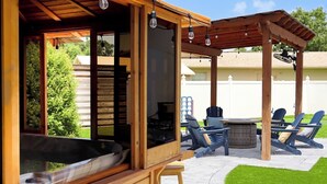 En utomhusplats med träinredning, komplett med ett bubbelbad, stolar och en pergola.