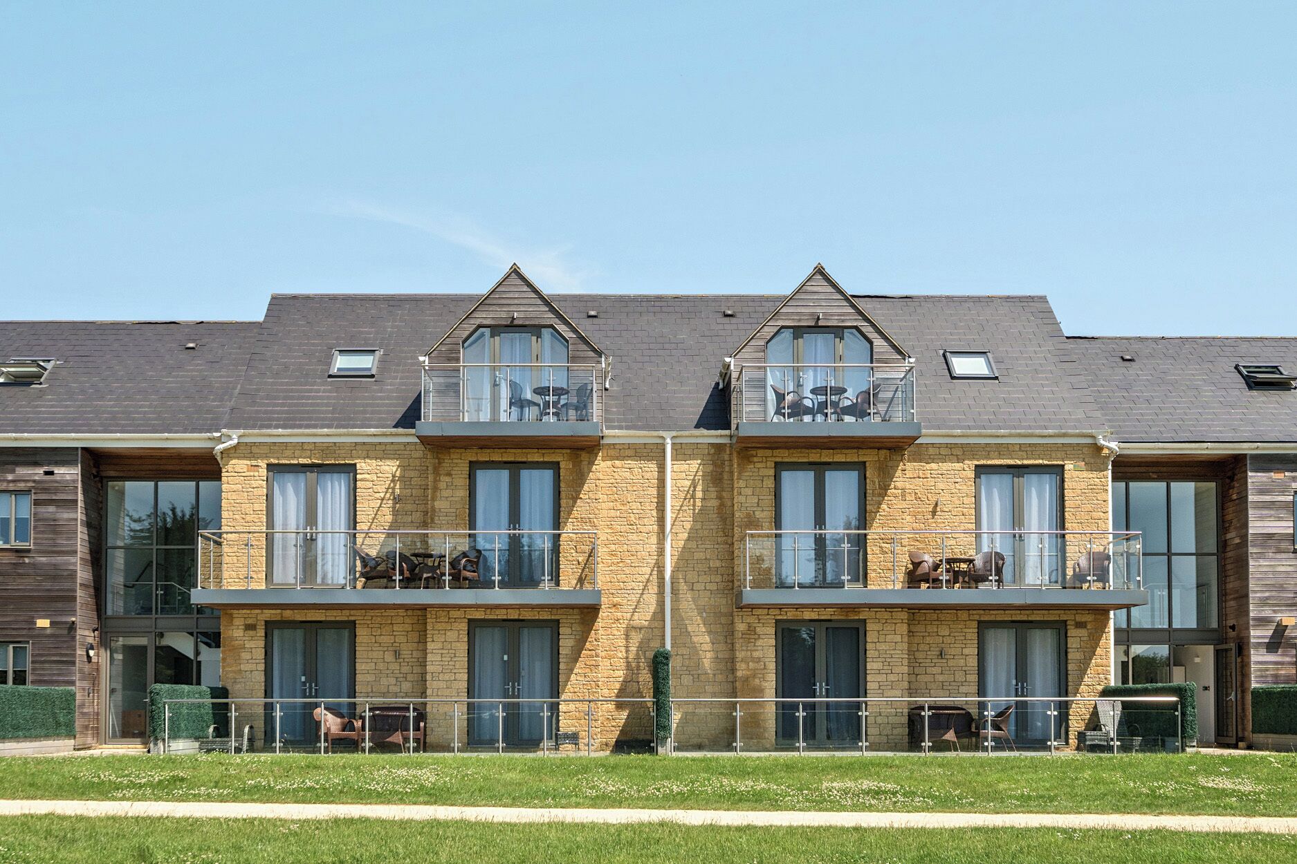 A modern residential building with two-story balconies, large windows, and a flat roof.