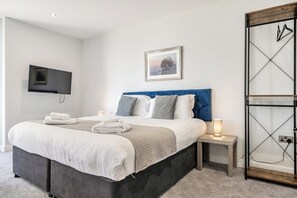 A modern hotel room with a bed, bedside tables, a TV, and a framed picture on the wall. - Cotswolds Apartment 2 Sleeps 4 (Chipping Norton)