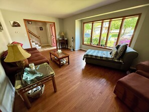 Ein Wohnzimmer mit Sofa, Couchtisch und Fenster mit Blick nach draußen.