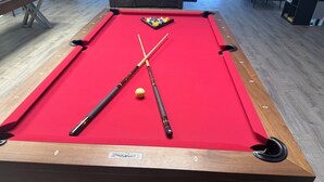 Taula de bitlles amb dues cues i una bola blanca, emmarcada en fusta i amb feliçroja.