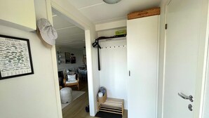 A hallway with a white door, a framed fish card, a wicker basket, and a chair. - 5 Star Holiday Home in Uddevalla (Uddevalla)