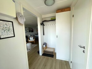 A hallway with a white door, a framed fish card, a wicker basket, and a chair. - 5 Star Holiday Home in Uddevalla (Uddevalla)