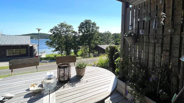 A wooden deck with a table, wicker baskets, and a hanging light fixture. - 5 Star Holiday Home in Uddevalla (Uddevalla)