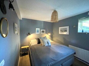 A bedroom with a bed, bedside tables, wall-mounted lamps, framed pictures, and a window with a view. - 5 Star Holiday Home in Uddevalla (Uddevalla)