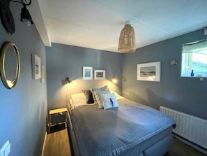 A bedroom with a bed, bedside tables, wall-mounted lamps, and framed pictures. - 5 Star Holiday Home in Uddevalla (Uddevalla)