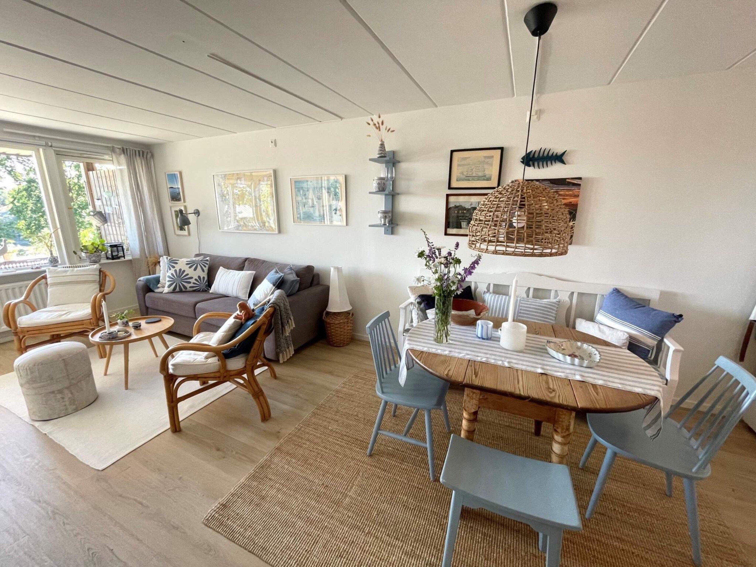 A living room with a sofa, chairs, a dining table with chairs, and artwork on the walls.
