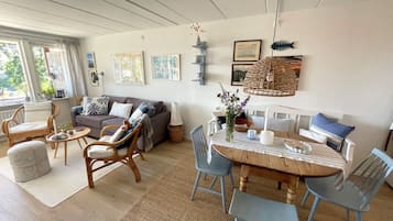 A living room with a sofa, chairs, a dining table with chairs, and artwork on the walls.