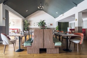 Ein moderner Essbereich mit hohen Decken, Holzwandabtrennungen und verschiedenen Sitzmöglichkeiten, darunter Sitzecken und Stühle.