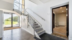 Ein modernes Interieur mit Treppe, Blick ins Freie und einer Tür zu einem weiteren Raum.