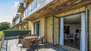 Eine moderne Wohnung mit einer Terrassenfläche, ausgestattet mit Korbmöbeln und Blick ins Innere.
