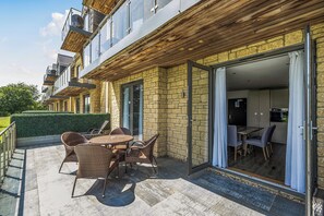 Eine moderne Wohnung mit einer Terrassenfläche, ausgestattet mit Korbmöbeln und Blick ins Innere.