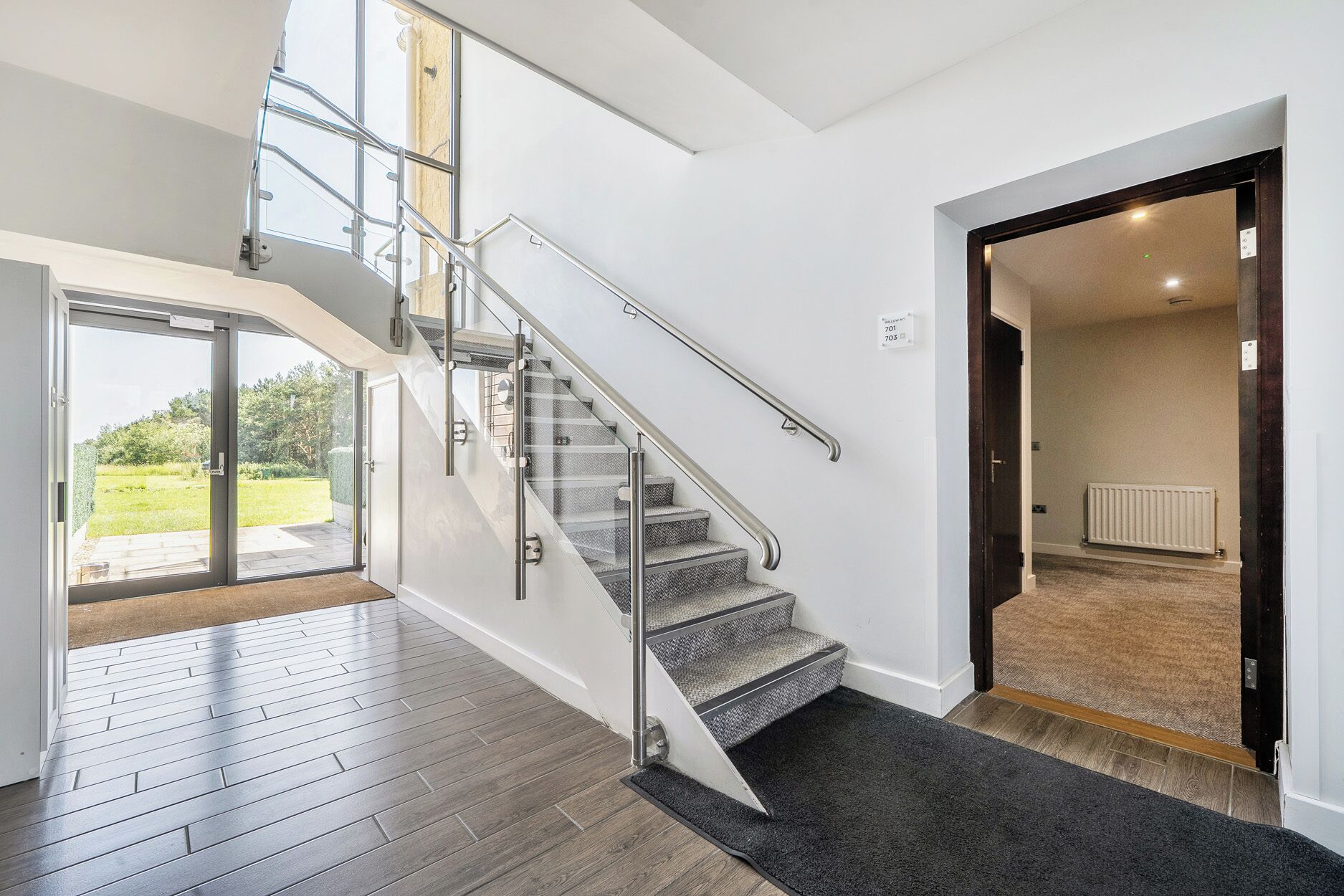 A modern interior with a staircase, a view to the outdoors, and a door leading to another room.