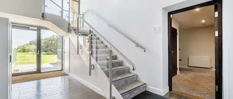 Un interior moderno con una escalera, vistas al exterior y una puerta que conduce a otra habitación.