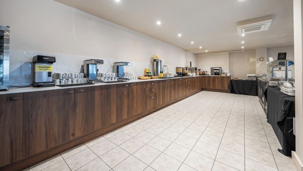 A modern kitchen with a long counter, coffee machines, and a sink. - Cotswolds Apartment 3 Sleeps 9 (Chipping Norton)