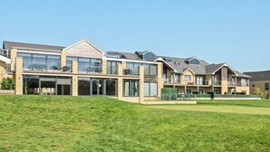 A modern residential building with multiple balconies, large windows, and a well-maintained lawn. - Cotswolds Apartment 3 Sleeps 9 (Chipping Norton)