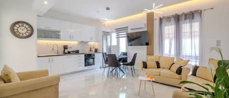 A modern living room with a sofa, coffee table, and a dining area with chairs and a table.