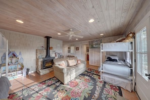 A cozy room with a fireplace, a sofa, a bunk bed, and a decorative rug. - Hunt River Retreat Porch, Kayaks & Hill Country (Hunt)