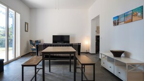 Ein zeitgemäßer Wohnbereich mit Essplatz, einer Couch, einem Fernseher und Kunstwerken an der Wand.