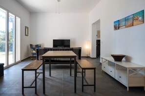 A modern living space with a dining area, a sofa, a television, and artwork on the wall. - Villa Sun and Moon by Ortigiaapartments (Plemmirio)