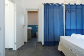 A hotel room with a bed, a bathroom with a sink and mirror, and a shower curtain. - Villa Sun and Moon by Ortigiaapartments (Plemmirio)