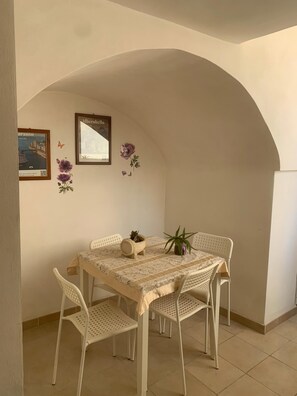 A dining area with a table and four chairs, a framed picture, and wall decorations.